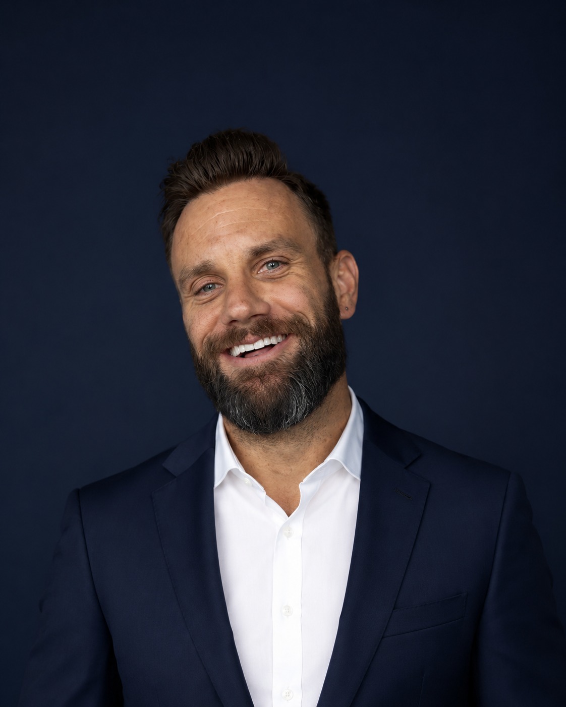 Christian Holmlund, founder of Vantage Point GTM — smiling warmly in a navy suit and white shirt against a deep navy studio backdrop.